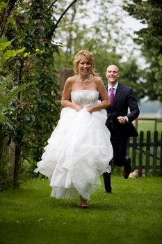 Beautiful bride running away from her new husband with a big smile on her face