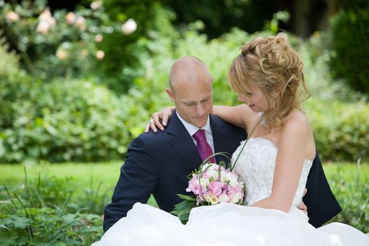 Beautiful bride and groom sitting together in the garden