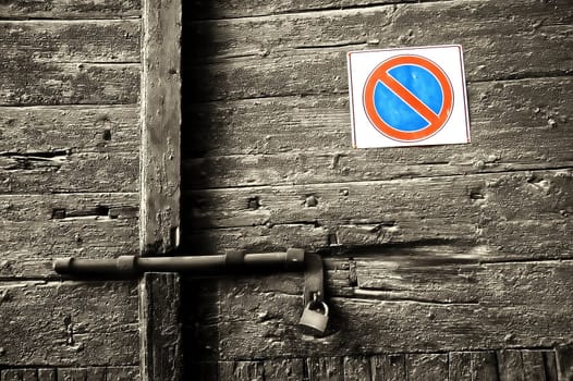 Forbidden sign on decayed wooden door with lock