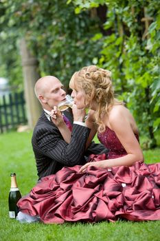 Newly wed couple having a toast in a lovely garden sitting in the grass