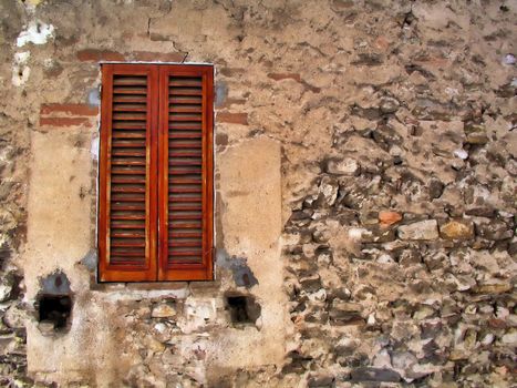 Old window with closed shutters and decayed stone wall