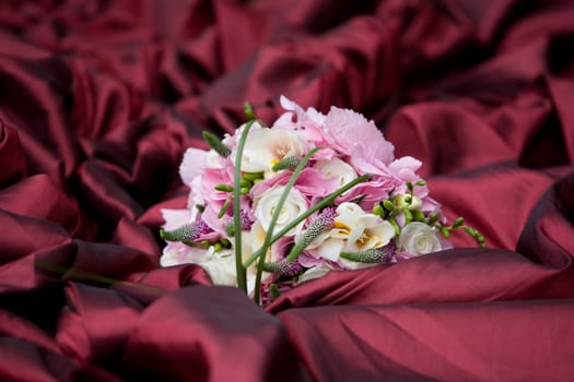 Wedding bouquet lying on the red wedding dress