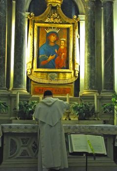 A Priest prepares the sacraments in a side chapel in a Venice Church.