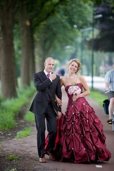 beautiful young bride and groom walking along a bicycle path on their wedding day