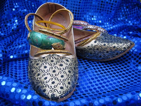 India ladies gold shoes and bangles on blue sequin material.