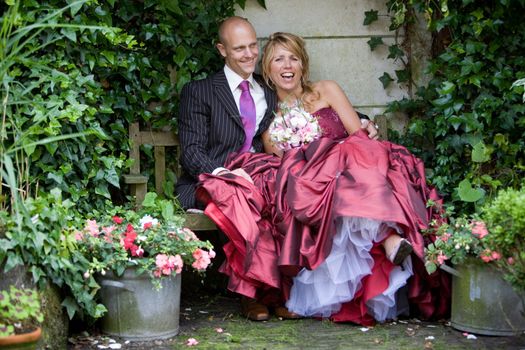 Lovely bride and groom sitting in a romantic setting clearly having fun