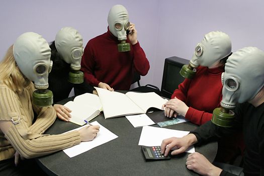 Industrial conference in gas masks behind a table