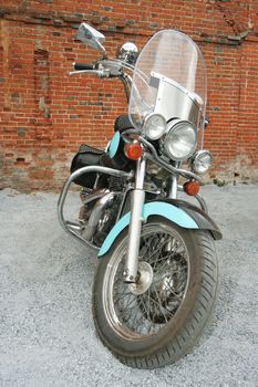 Old blue motorcycle at a brick wall