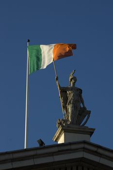 Statue and Irish Flag on top of the GPO in Dublin City shot from below with plenty of bright blue sky