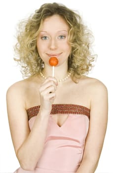 The laughing young girl with light hair in a pink dress with a pink sugar candy in a hand
