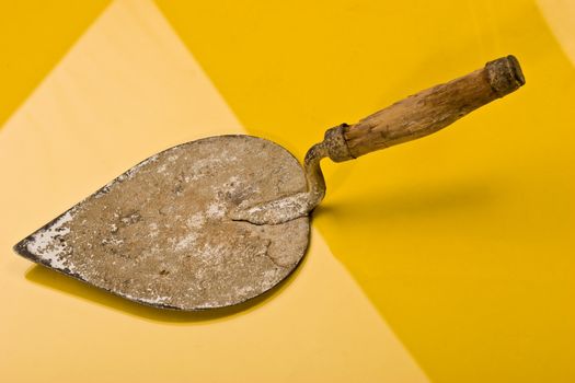 Brick trowel on the reflective yellow surface
