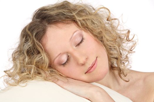 The young girl with light hair close up sleeps on a white pillow on a white background
