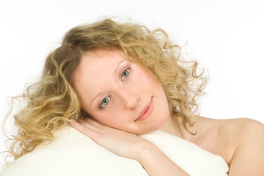 The young girl with open eyes and light hair lays on a white pillow on a white background 
