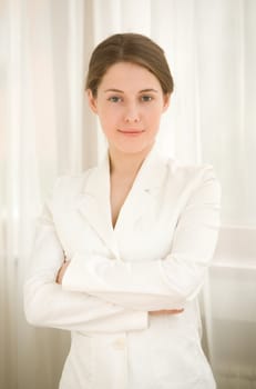 The business woman in a white jacket with dark hair near a window
