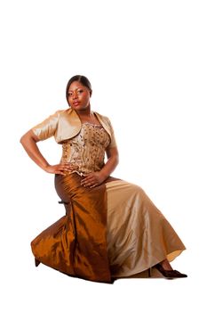 Beautiful African American woman in brown with gold dress, sitting, isolated