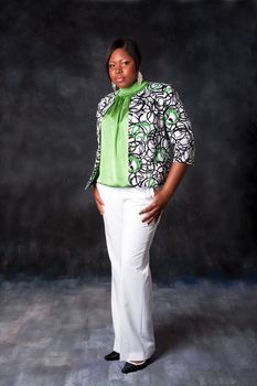Beautiful African American business woman in white pants and green shirt with blazer standing