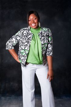 Beautiful African American business woman in white pants and green shirt with blazer standing and laughing with huge smile showing teeth