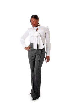 Beautiful African American business woman with attitude dressed in a white shirt and gray pants standing, hands on hip, isolated
