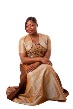 Beautiful African American woman in brown with gold dress, sitting, isolated