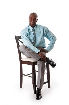 Handsome African American business man smiling sitting on chair, wearing sea green shirt and gray pants, isolated