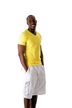 Handsome sporty African American man in yellow shirt and white shorts standing with hands in pocket and big smile, isolated