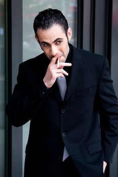 Secret surveillance photo of a Caucasian mafia business man smoking a cigarette dressed in a black suit