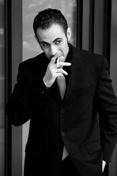 Secret surveillance photo of a Caucasian mafia business man smoking a cigarette dressed in a black suit