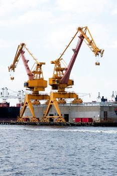 Heavy duty yellow cranes on rails for loading cargo onto ships at a port terminal