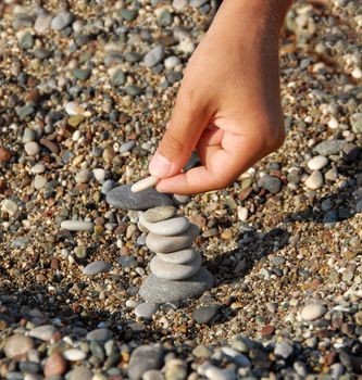 child hands building a rocks stack carefully