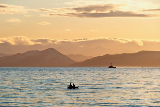 Fishermen by a boat in an evening bay