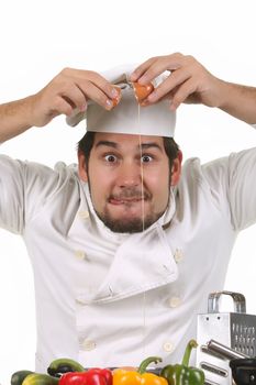 young funny chef cracking an egg, isolated on white