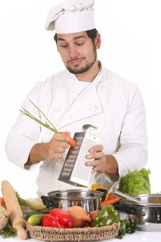 young chef preparing lunch and cutting carrot with stainless grater