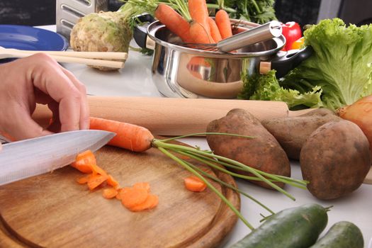 chef preparing lunch and cutting carrot with knife