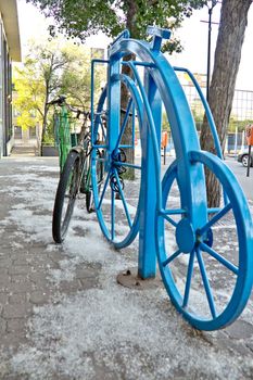 An old bike tied to a bike rack with a shape of a bike