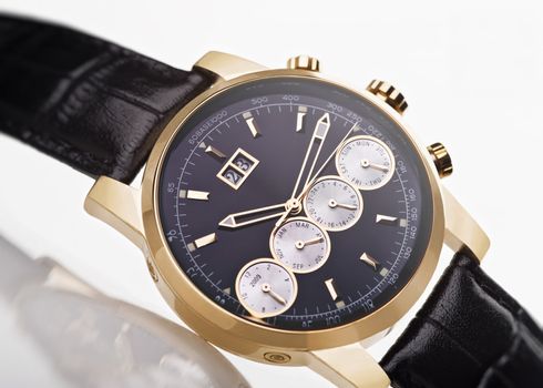 gold men's wristwatch with black leather strap on a white background