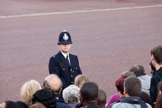LONDON - JUNE 11: British policeman observes the crowd of spectators during the Trooping the Color ceremony in London, England on June 11, 2011. Ceremony is performed by regiments on the occasion of the Queen's Official Birthday