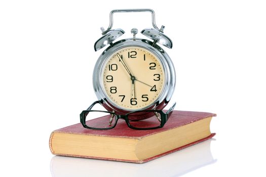 book with alarm clock and eyeglasses on white background