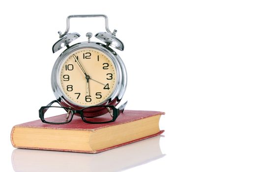 book with alarm clock and eyeglasses on white background