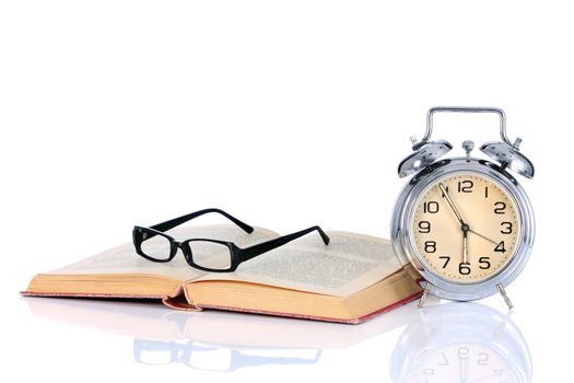 book with alarm clock and eyeglasses on white background