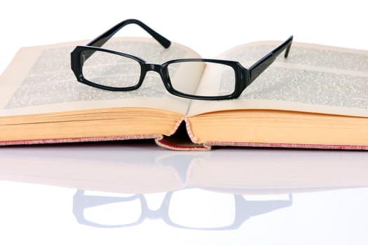 book and eyeglasses on white background