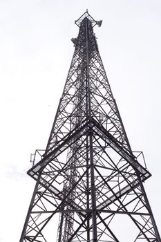 Metal tower with various communication antennas isolated on white.