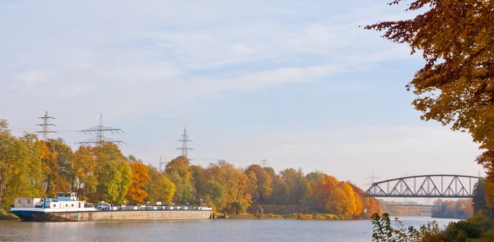 German freight ship anchoring on canal in fall-colored landscape