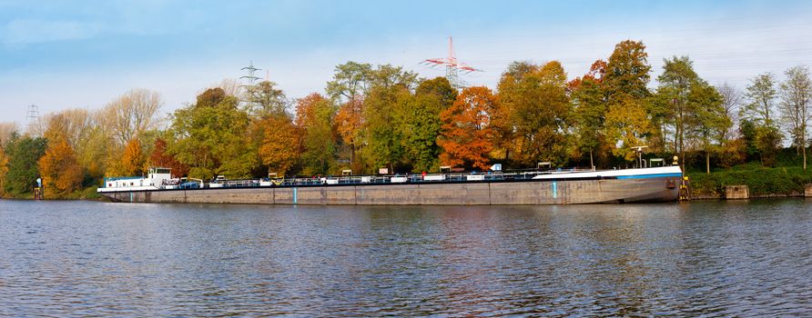 German freight ship anchoring on canal in fall-colored landscape