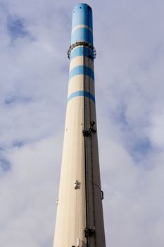 White-blue industrial high concrete chimney.