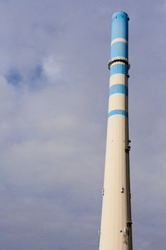 White-blue industrial high concrete chimney.