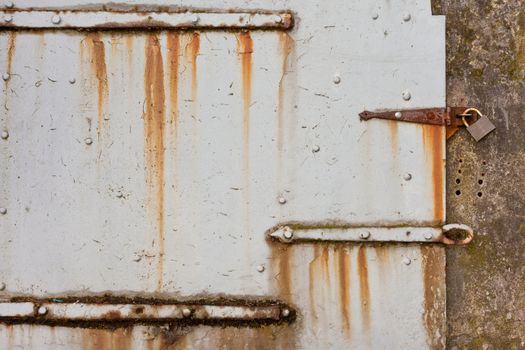 Grungy old steel hatch door secured by padlock