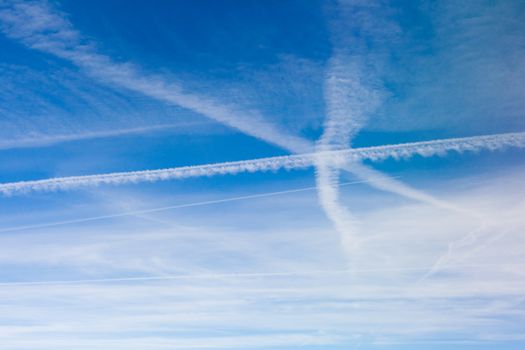 Lots of criss-crossing aircraft vapor trails in the blue sky.