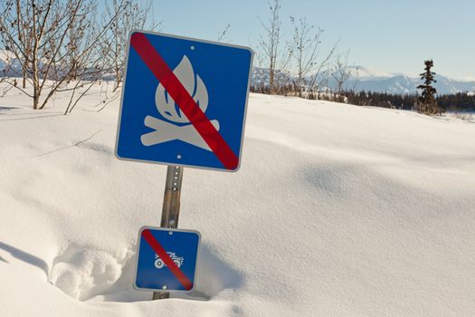 Absurd "open fire prohibited" sign sticking out of snowdrift.