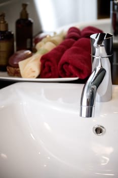 tap of a clean washbasin with bathing supplies on the background