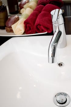 tap of a clean washbasin with bathing supplies on the background